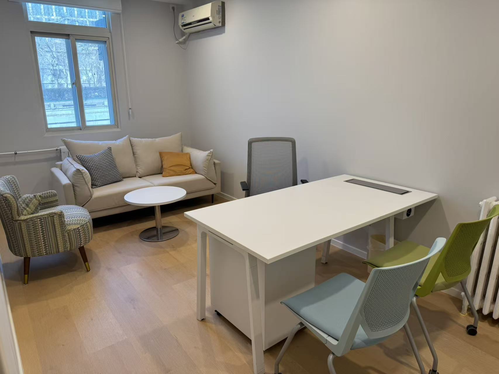 Bright office with a sofa, colourful accent chairs and a calm garden view